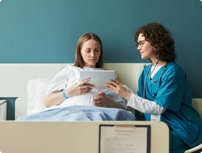 Pharmacist counseling a patient at the bedside using a tablet